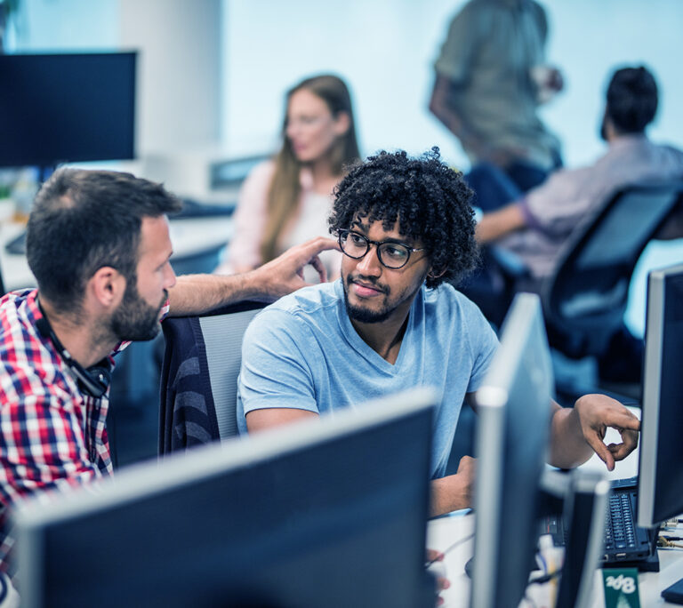 Photo of diverse colleagues looking at a computer screen together in an office