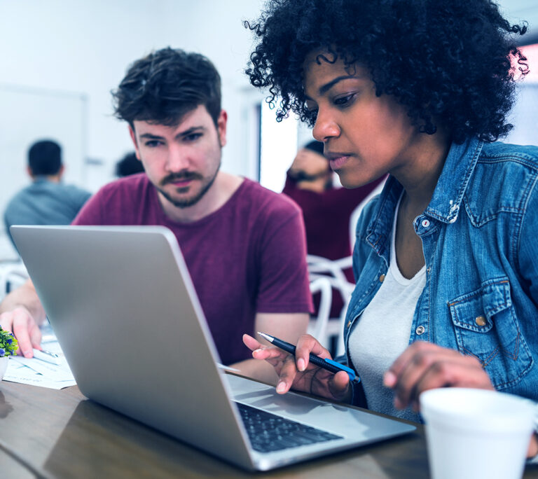 Two diverse colleagues working together on a laptop